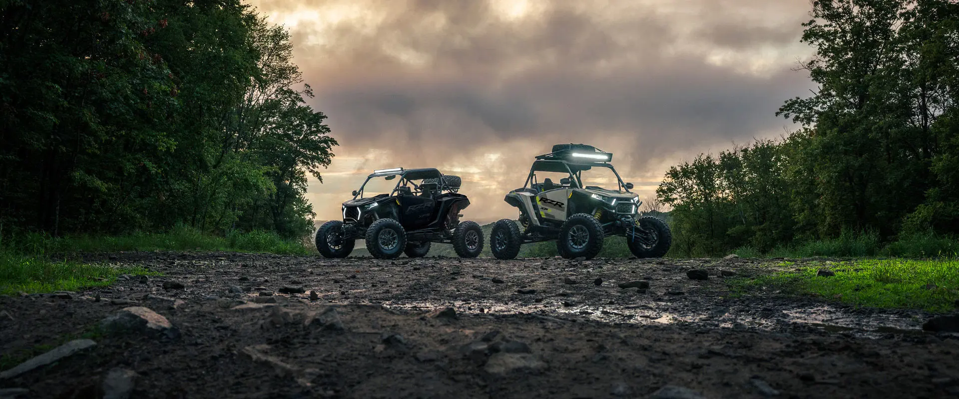 Two 2027 Polaris RZR XP S side-by-sides with lights illuminated.