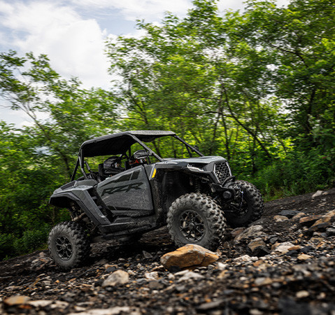 2 riders in a 2027 Polaris RZR XP Ultimate side-by-side crawling over rocky terrain.