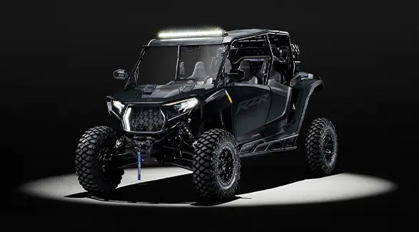 A 2027 Polaris RZR XP 4 Ultimate side-by-side with a light bar accessory entrenched in light while parked in a dark garage.