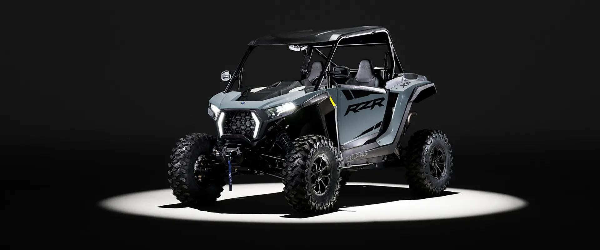 A 2027 Polaris RZR XP Ultimate side-by-side entrenched in light while parked in a dark garage.