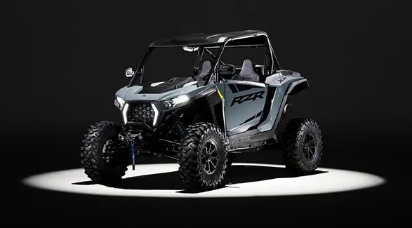 A 2027 Polaris RZR XP Ultimate side-by-side entrenched in light while parked in a dark garage.