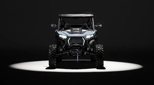 Front end view of a 2027 Polaris RZR XP Ultimate SxS entrenched in light while parked in a dark garage.