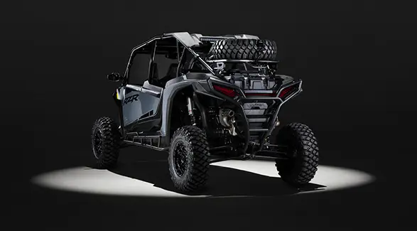 Rear view of a 2027 Polaris RZR XP 4 Ultimate SxS entrenched in light while parked in a dark garage.