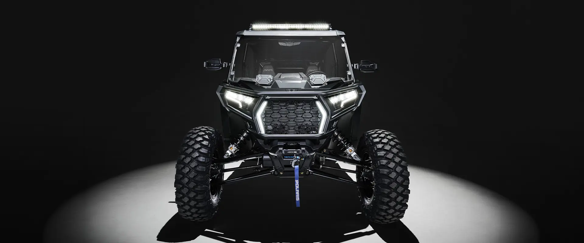 Front end view of a 2027 Polaris RZR XP 4 Ultimate SxS with illuminated headlights.