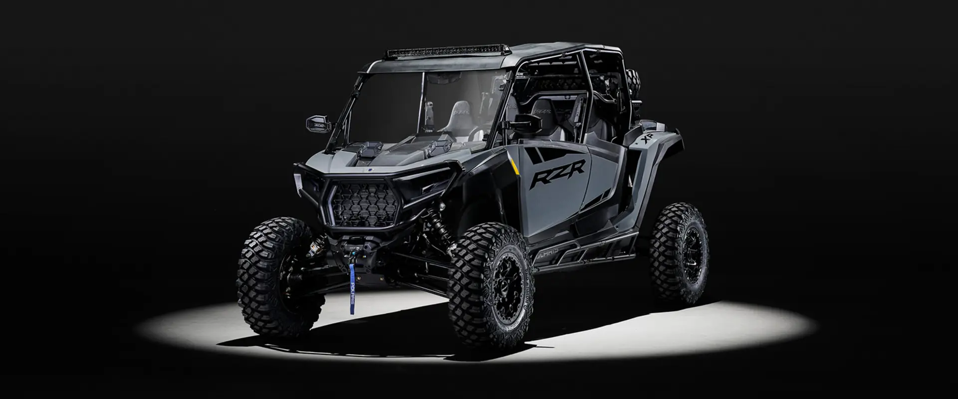 Angled view of a 2027 Polaris RZR XP 4 Ultimate SxS entrenched in light and parked in a dark garage.