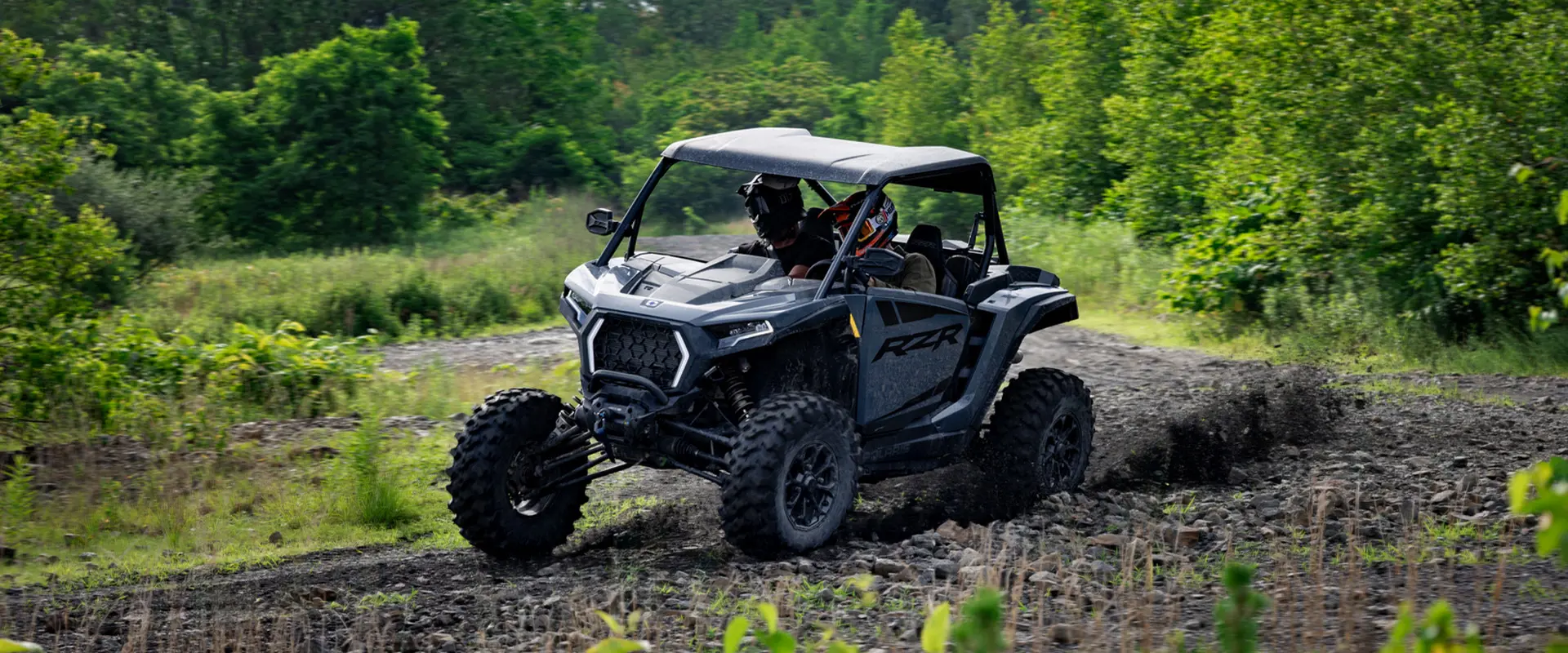 2 riders in a 2027 Polaris RZR XP Ultimate SxS taking a tight corner with ease.