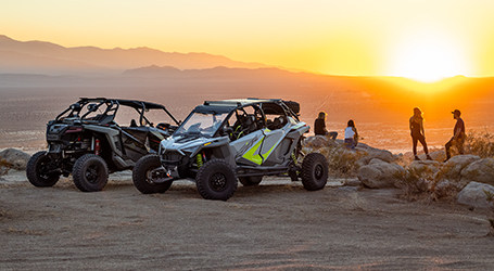 Group of people watching the sunset around two Polaris RZR Turbo R vehicles