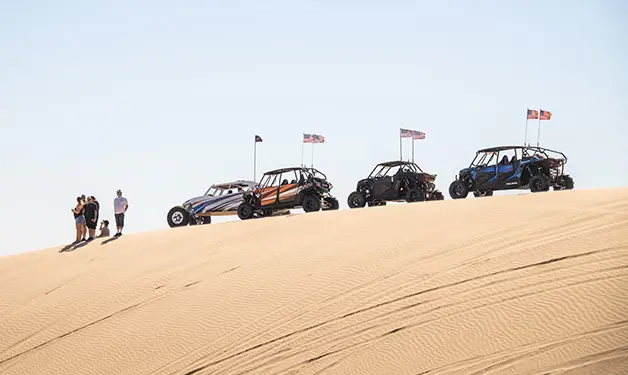 4 polaris rzr side-by-side estacionados sobre una duna