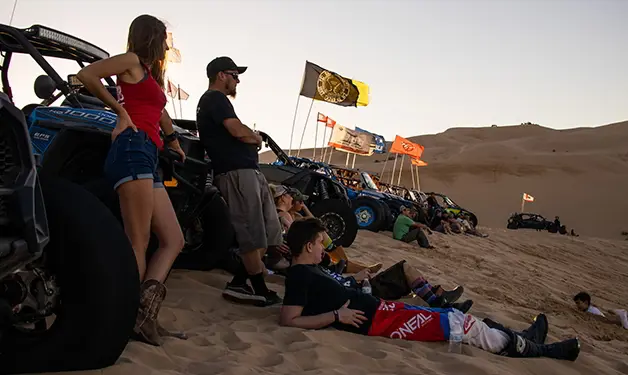 personas relajándose junto a sus side-by-side rzr en camp rzr