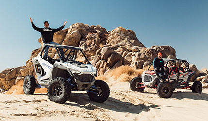 Three men stand in front of a vehicle and a RZR at Speed Vegas