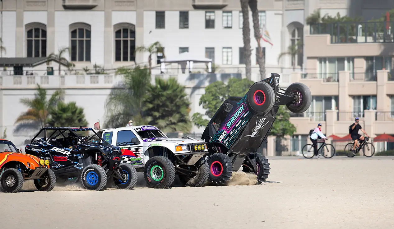 grupo de vehículos que compiten con el Hoonigan RZR pro R en la playa
