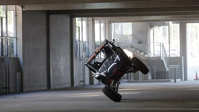 El Hoonigan RZR pro R se desplaza en un estacionamiento en sus dos ruedas laterales