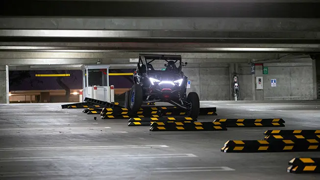 El Hoonigan RZR Pro R conduciendo sobre topes dentro de un estacionamiento