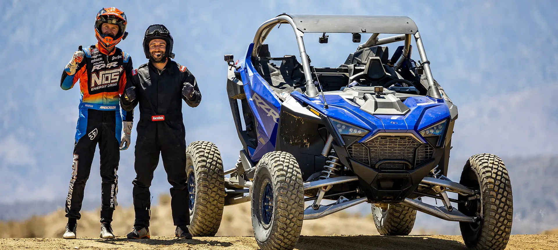 RJ Anderson and other driver smiling and standing next to a RZR