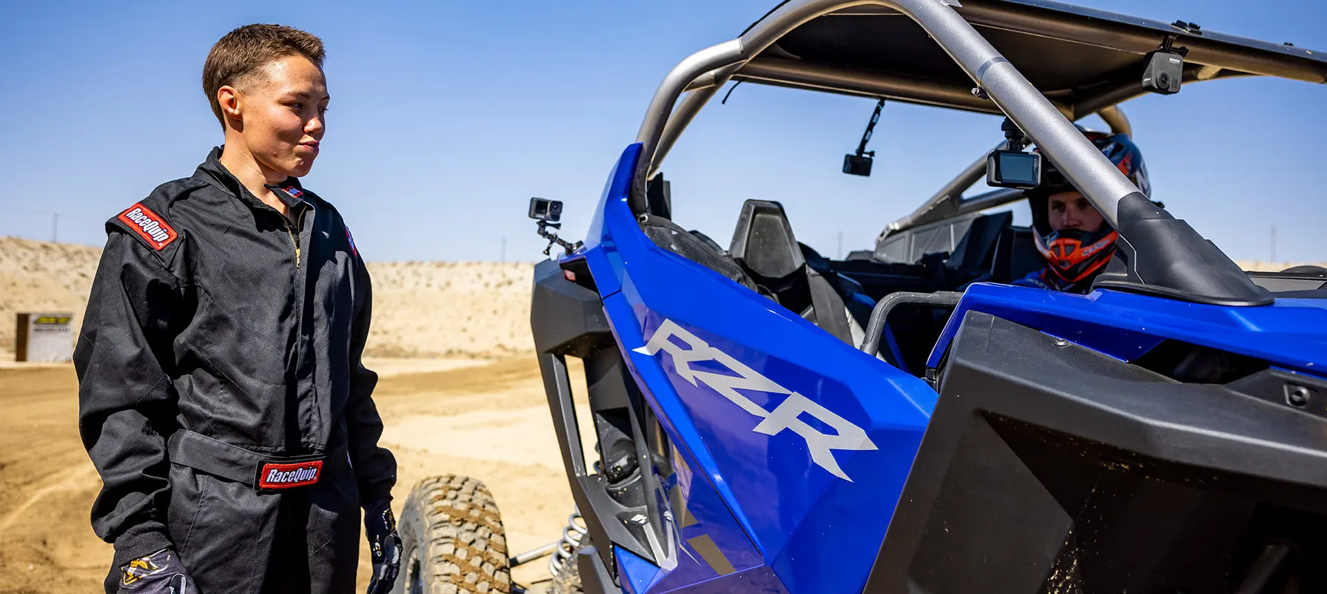 A person standing next to a RZR Pro R vehicle