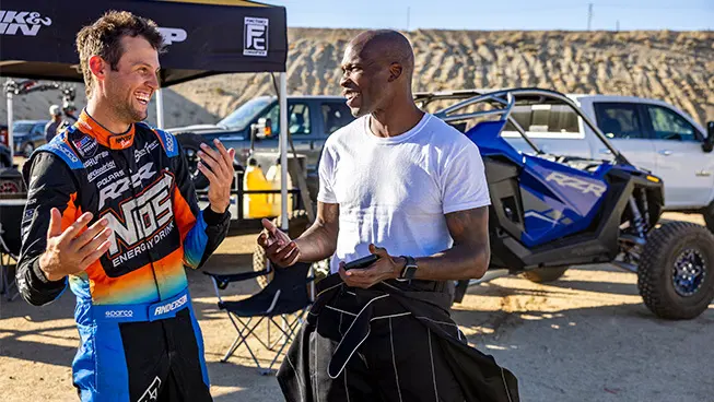 RJ Anderson and a man chatting near some parked RZRs