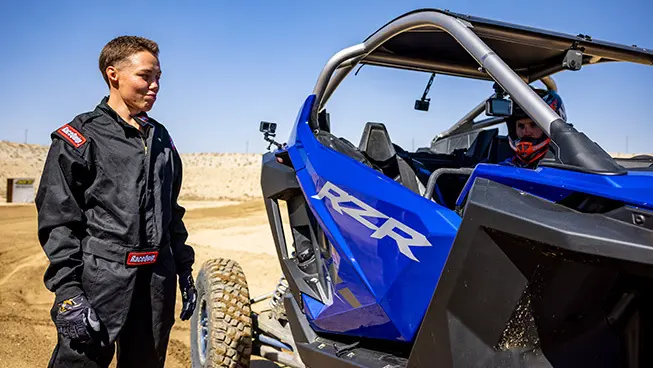 A person standing next to a RZR Pro R vehicle
