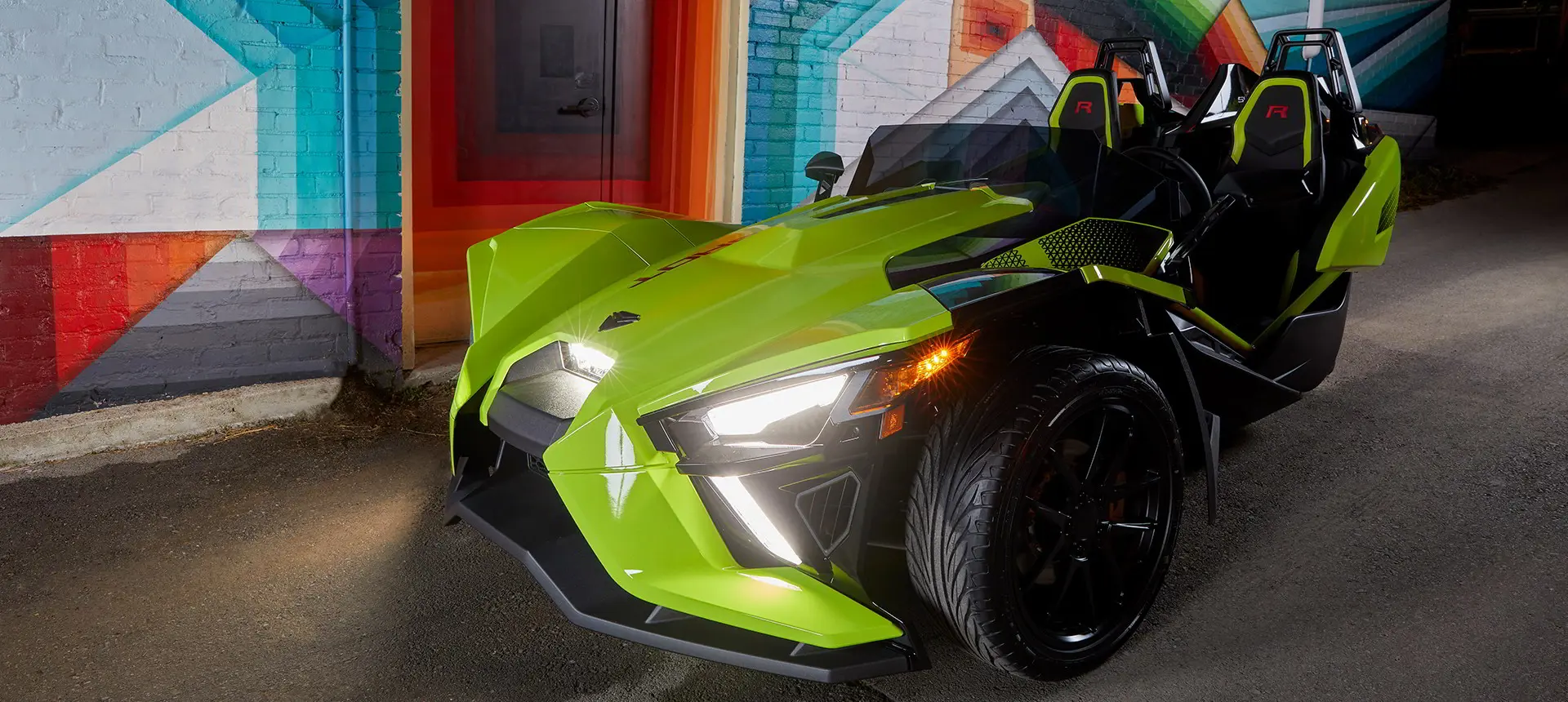 Slingshot R LE vehicle parked next to four people chatting