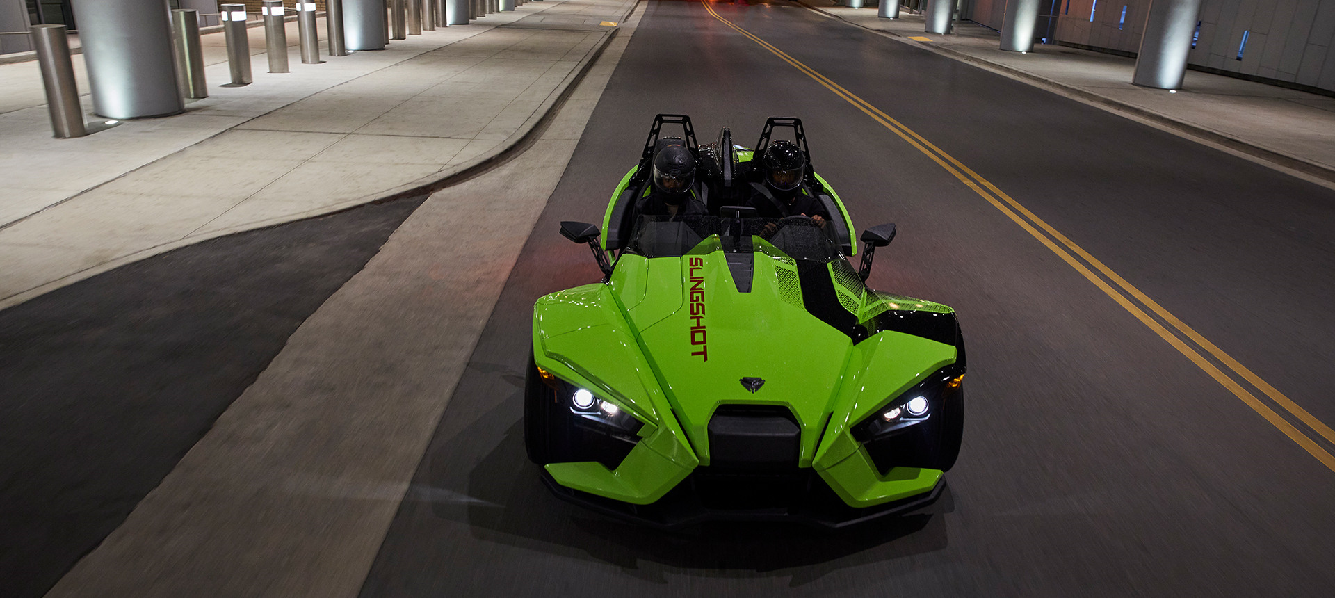 A Slingshot R vehicle riding on a road during the night