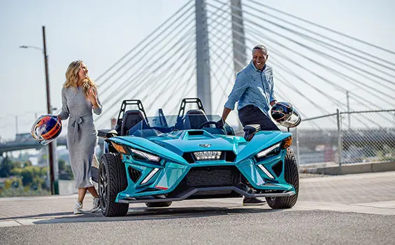 conductor y pasajero saliéndose de una motocicleta de tres ruedas polaris slingshot r