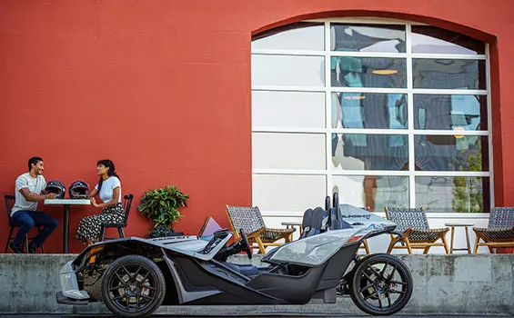 people getting lunch at a table near their polaris slingshot s