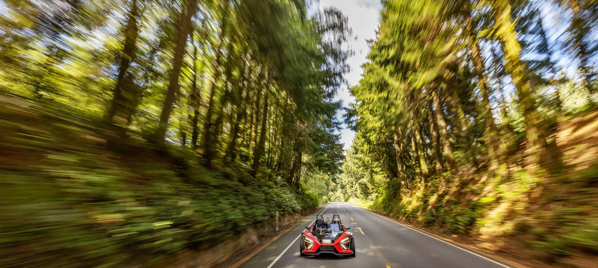 Polaris Slingshot Signature LE conducida en una carretera en un bosque