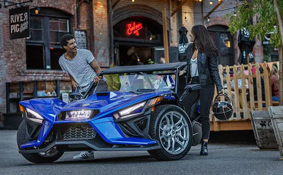 driver and rider stepping out of their polaris slingshot SL three-wheeled motorcycle