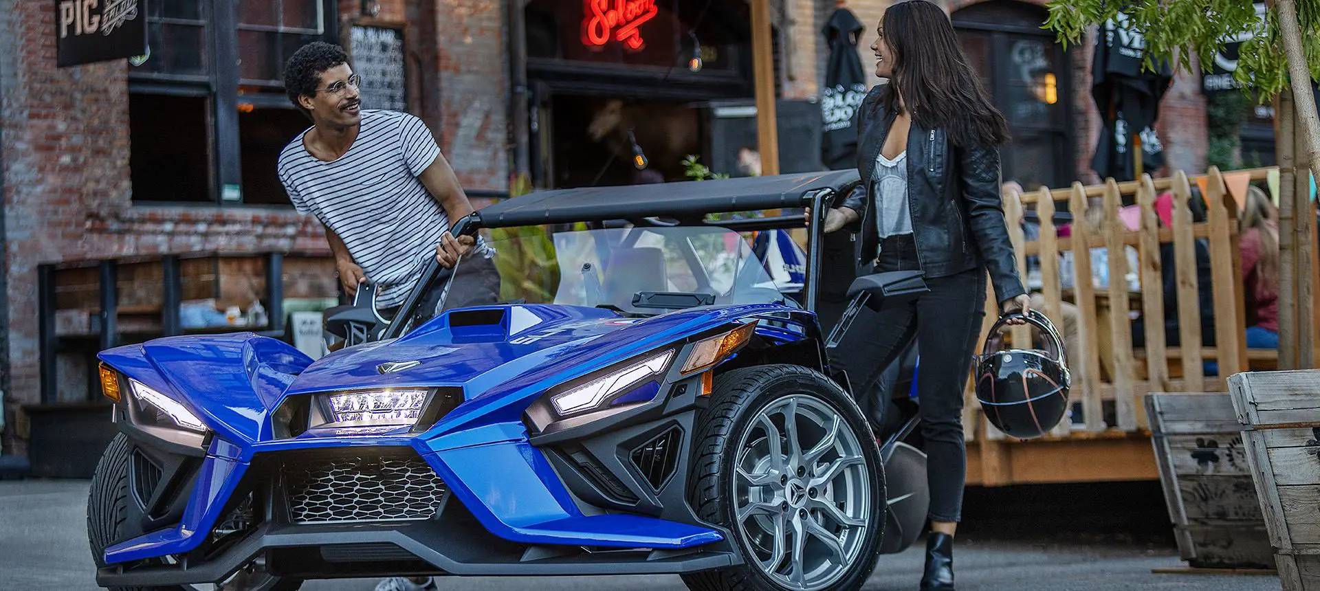 driver and rider stepping out of their polaris slingshot SL three-wheeled motorcycle