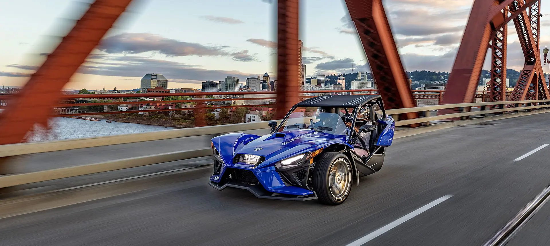 polaris slingshot SL three-wheeled motorcycle cruising on a bridge