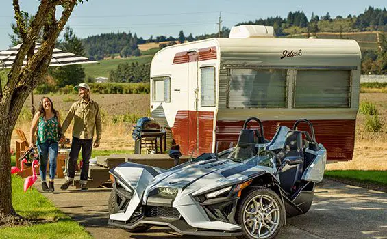 couple holding hands near their polaris slingshot SL three-wheeled motorcycle