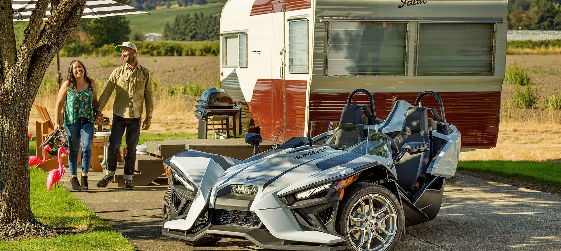 couple holding hands near their polaris slingshot SL three-wheeled motorcycle