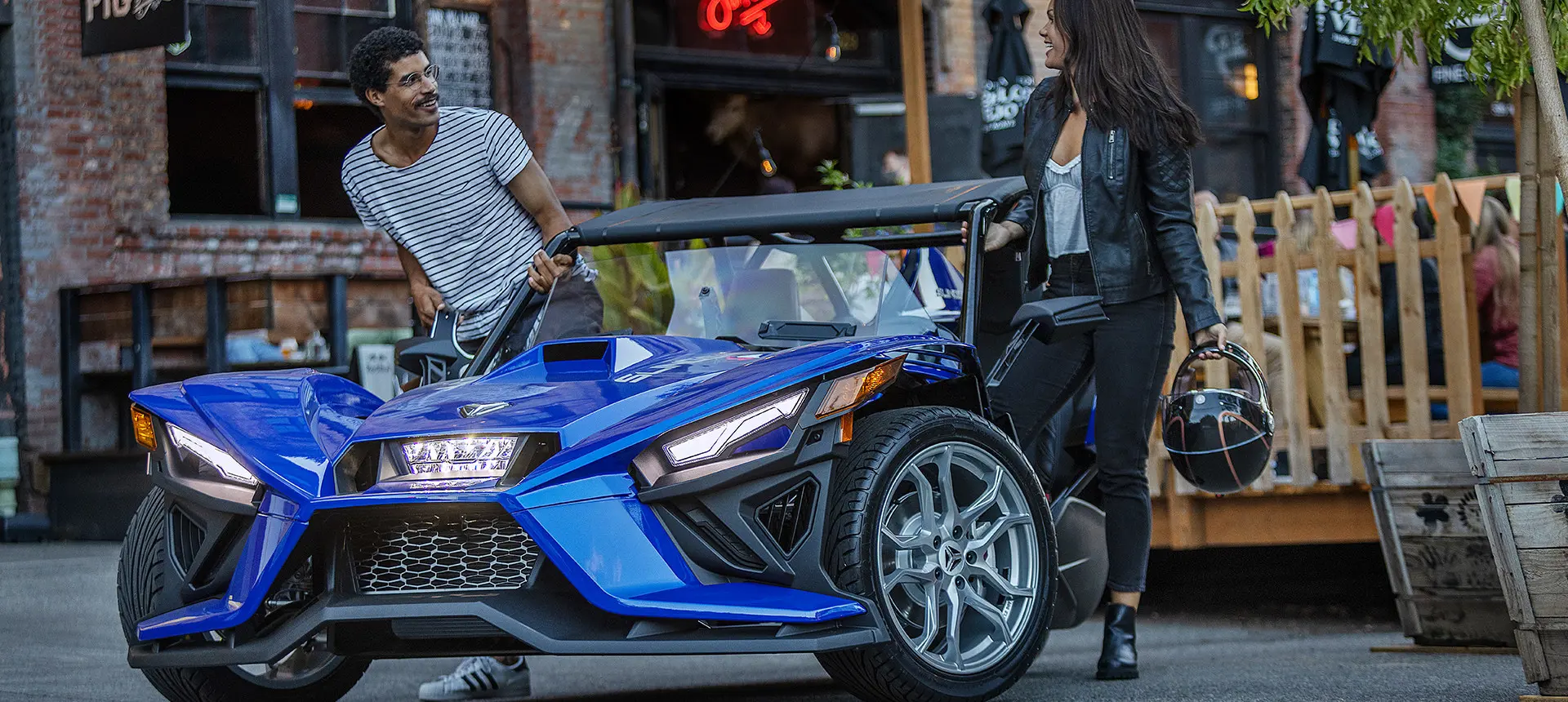 Man and woman getting on a Polaris Slingshot