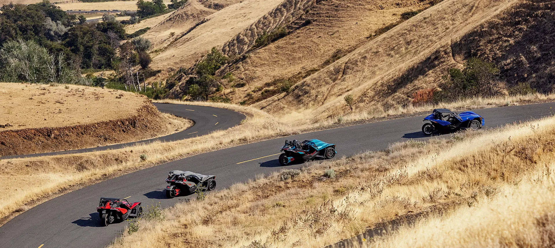 Four Polaris Slingshot vehicles on the road