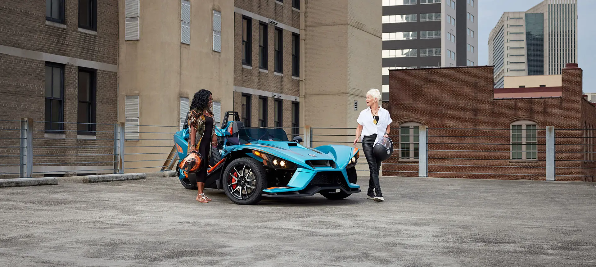 Deux femmes s’éloignant d’une moto à trois roues polaris slingshot r sarcelle pacifique