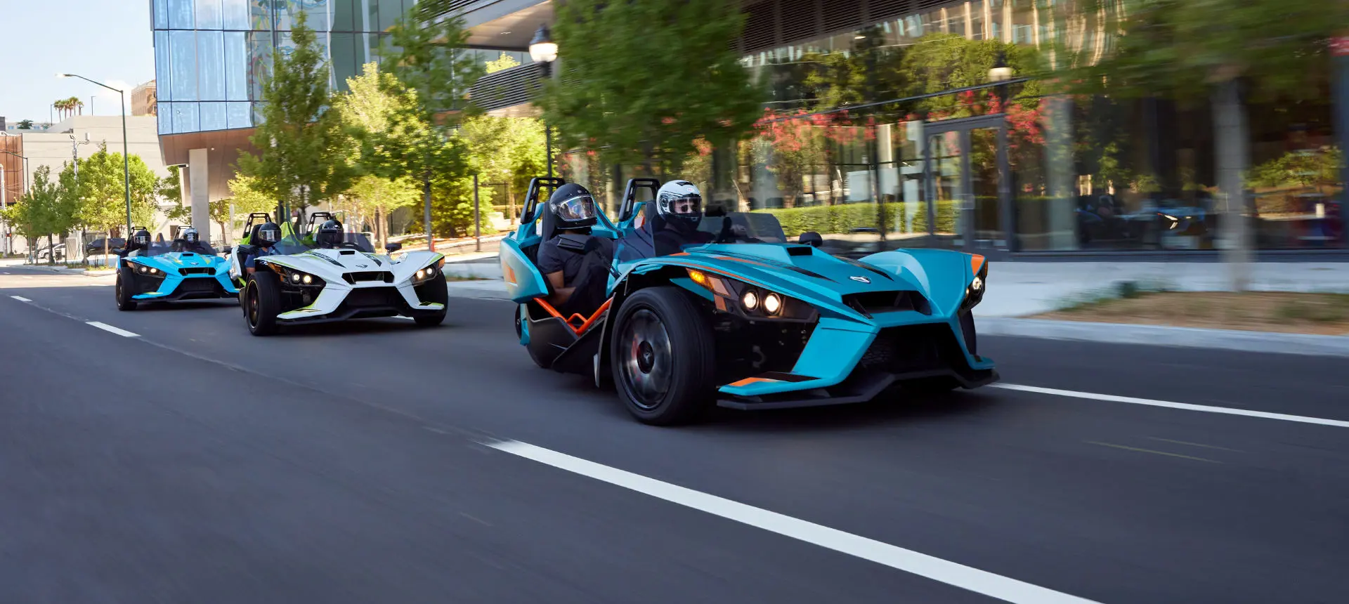trois rodsters polaris slingshot r circulant dans une rue urbaine