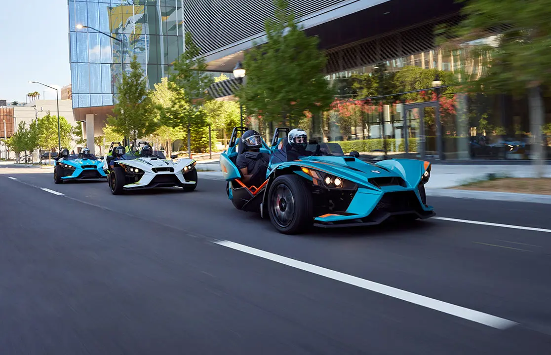 trois rodsters polaris slingshot r circulant dans une rue urbaine