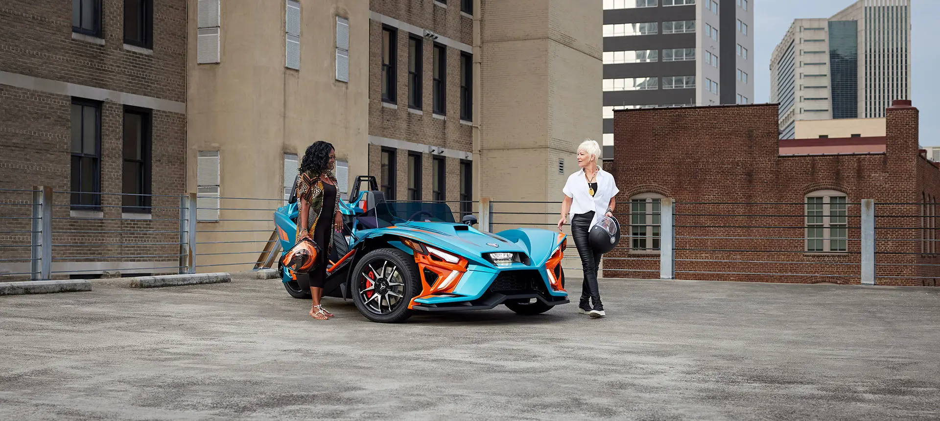 2 women walking away from a pacific teal haze polaris slingshot r three-wheeled motorcycle