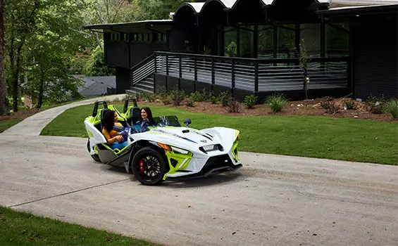 2 women in a lime dream polaris slingshot r three-wheeled motorcycle