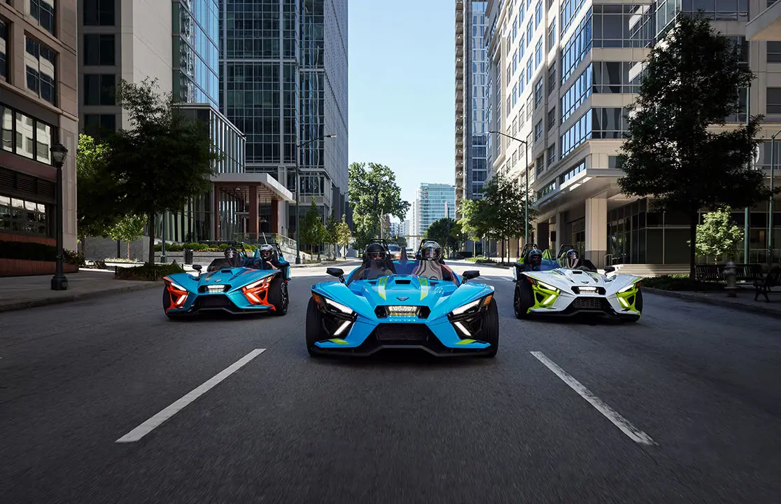 3 polaris slingshot r roadsters driving down a city street