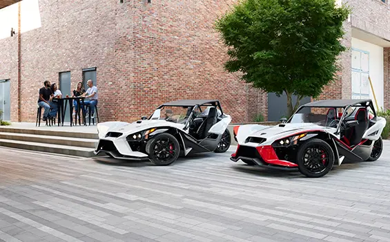 two people walking towards a 2024 polaris slingshot ROUSH® edition three-wheeled motorcycle