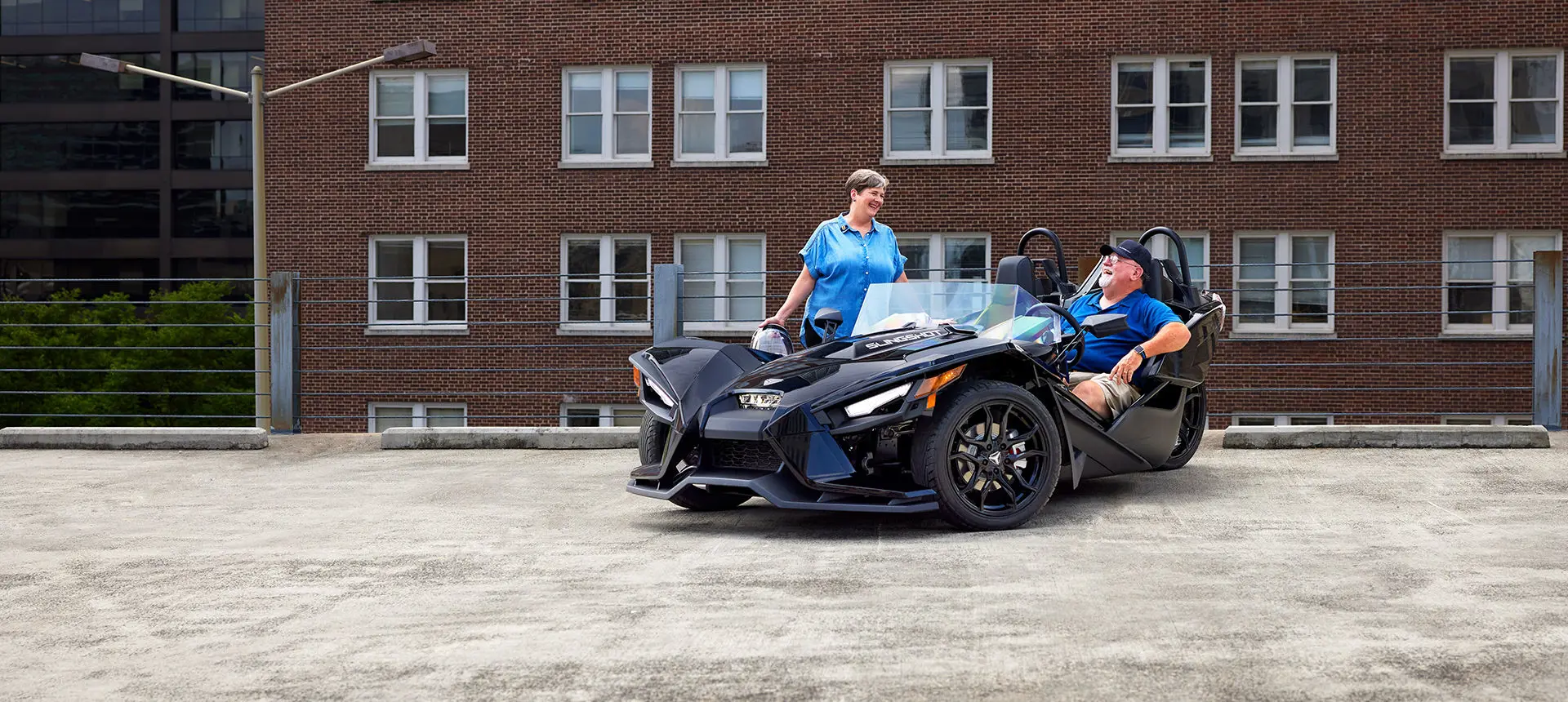 woman stepping into a polaris slingshot s while a man laughs in the drivers seat