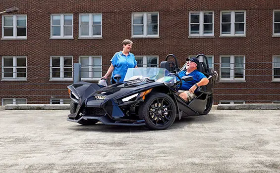 woman stepping into a polaris slingshot s while a man laughs in the drivers seat
