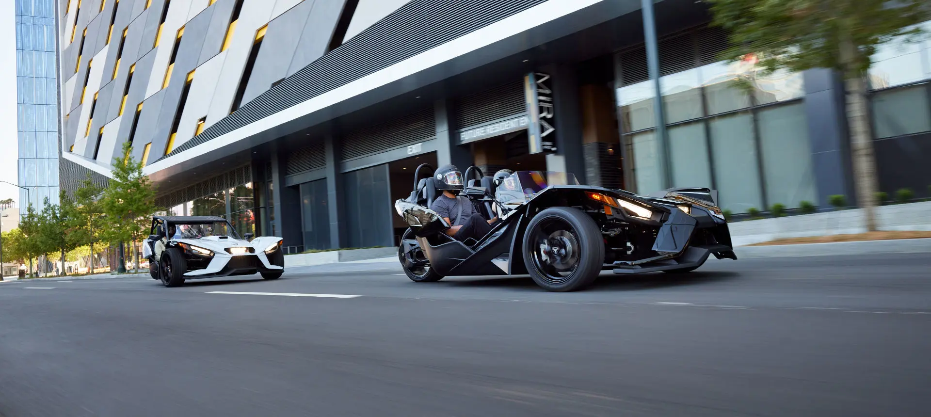 2 polaris slingshot s motorcycles on a city street