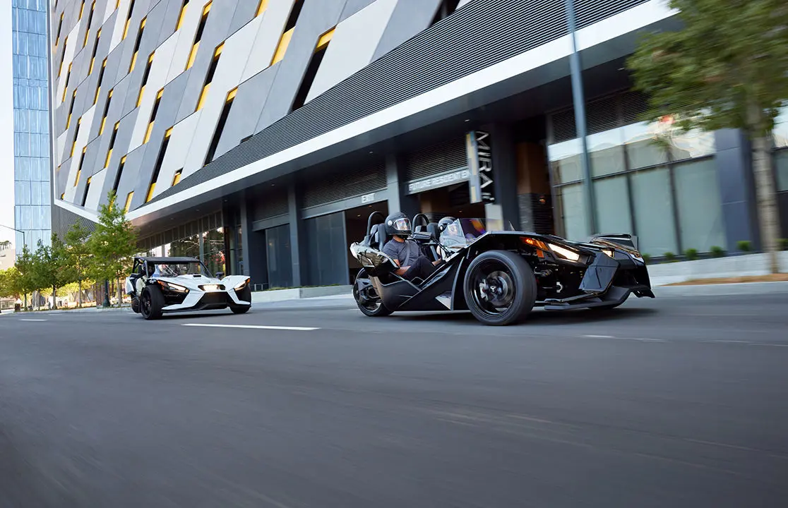 2 polaris slingshot s motorcycles on a city street