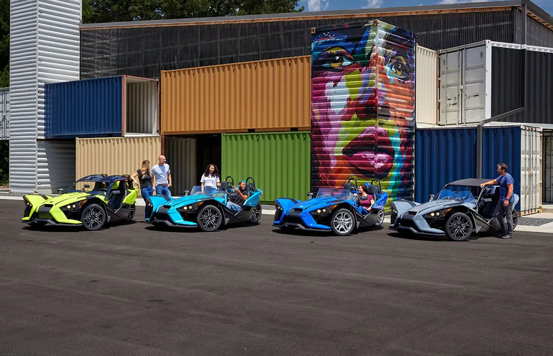 4 sets of people hanging around near their polaris slingshot sl three-wheeled roadsters