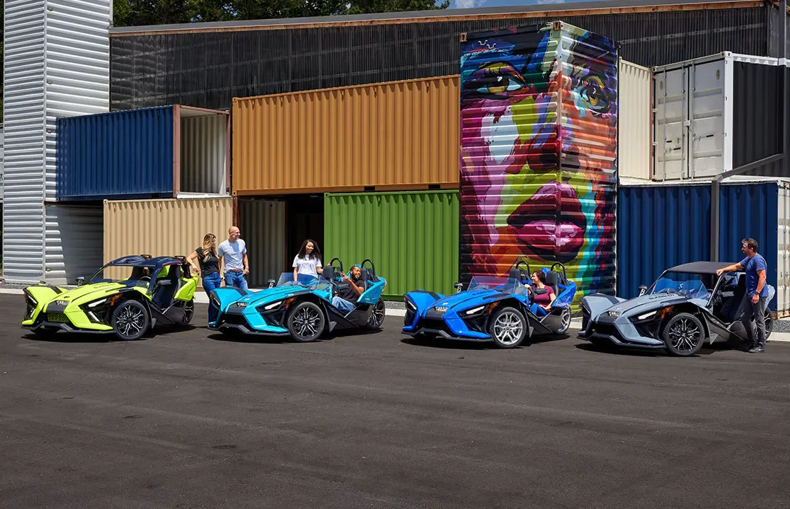 vista delantera de dos conductores en una motocicleta de tres ruedas polaris slingshot sl en azul cobalto