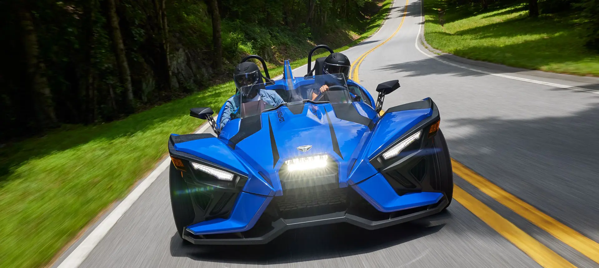 Pareja alejándose de una motocicleta de tres ruedas polaris slingshot en color gris tormenta