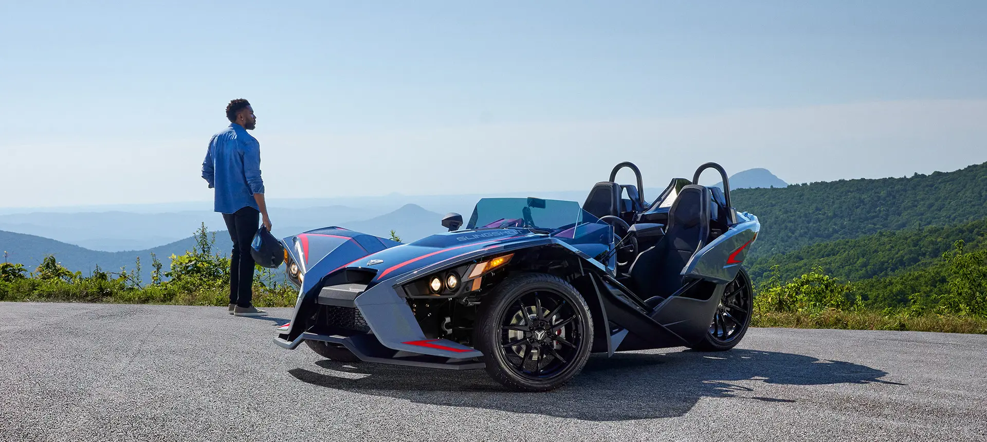homme debout à côté d’une moto à trois roues polaris slr rouge ombré