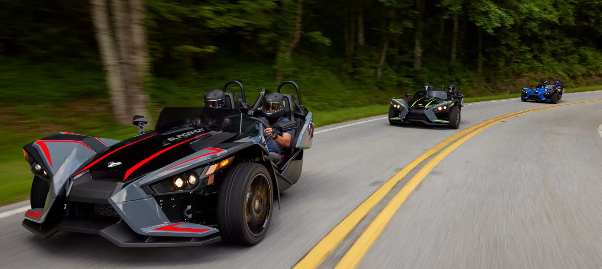 trois motos à trois roues polaris slingshot slr roulant sur une route
