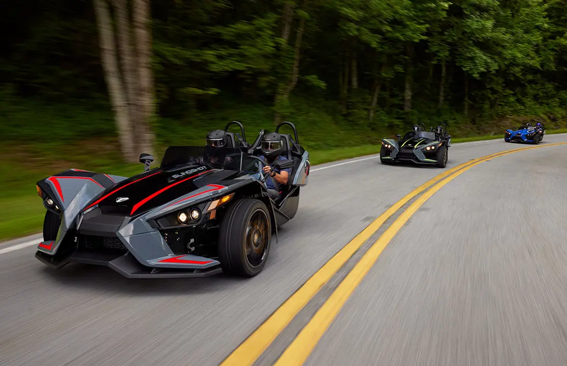 trois motos à trois roues polaris slingshot slr roulant sur une route